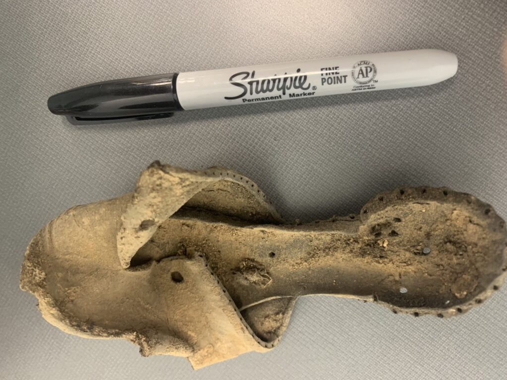 One shoe from the early 1800s from the Teen Center alongside a sharpie.
